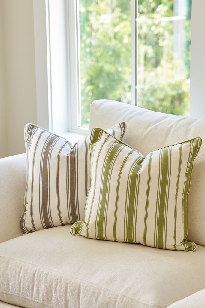 Striped pillows on a beige sofa with a window in the background