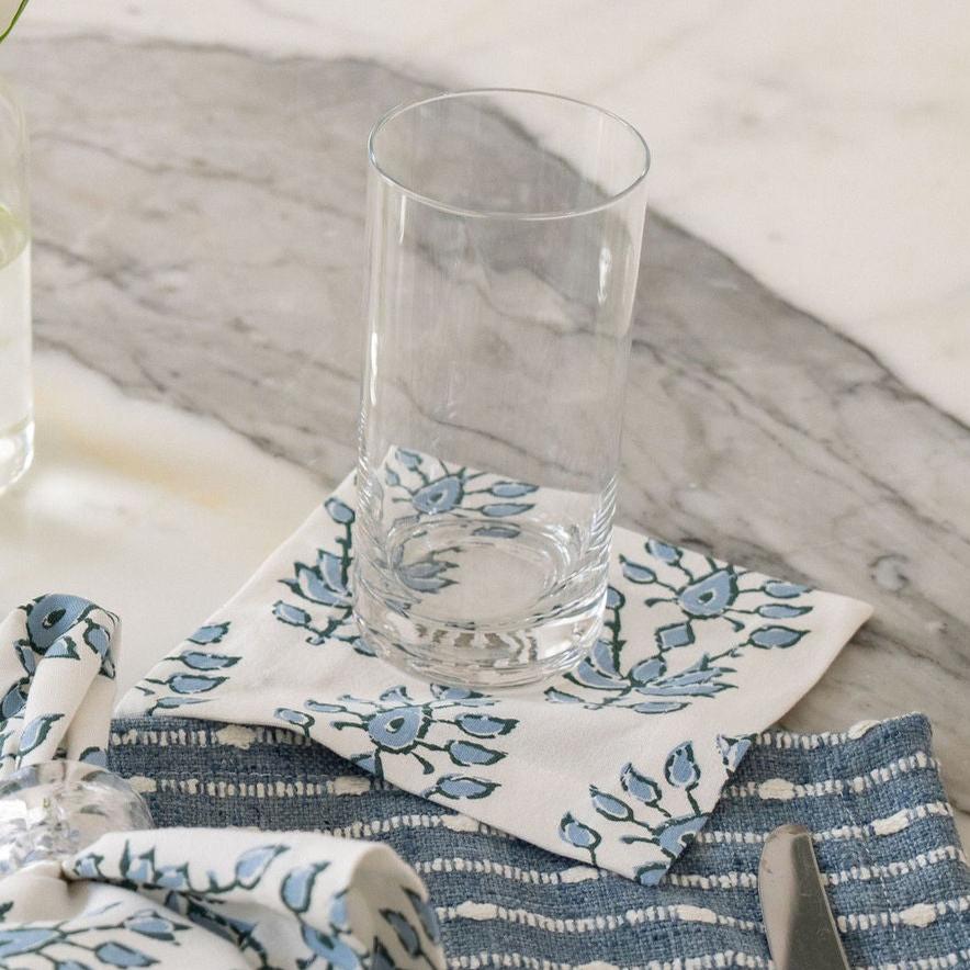 blue and white floral cocktail napkins with a glass of water sitting atop 