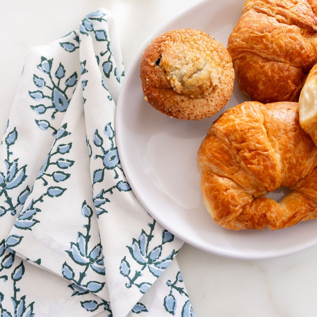 blue and white dinner napkin beside breakfast pasteries